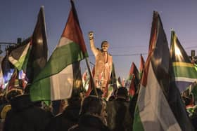 People raise flags and placards as they gather around a statue of late South African president Nelson Mandela to celebrate a landmark "genocide" case filed by South Africa against Israel at the International Court of Justice, in the occupied West Bank city of Ramallah on January 10, 2024. The ruling African National Congress (ANC) has long been a firm supporter of the Palestinian cause, often linking it to its own struggle against the white-minority government, which had cooperative relations with Israel. (Photo by MARCO LONGARI / AFP) (Photo by MARCO LONGARI/AFP via Getty Images)