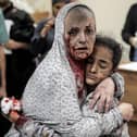 An injured Palestinian woman covered in dust and blood hugs an injured girl child at the hospital following the Israeli bombardment of Khan Yunis in the southern Gaza Strip on November 15, 2023. More than 11,000 people have been killed in relentless Israeli bombardment of the Gaza Strip, according to the health ministry. (Photo by Belal KHALED / AFP) (Photo by BELAL KHALED/AFP via Getty Images)