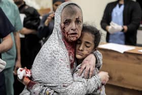 An injured Palestinian woman covered in dust and blood hugs an injured girl child at the hospital following the Israeli bombardment of Khan Yunis in the southern Gaza Strip on November 15, 2023. More than 11,000 people have been killed in relentless Israeli bombardment of the Gaza Strip, according to the health ministry. (Photo by Belal KHALED / AFP) (Photo by BELAL KHALED/AFP via Getty Images)