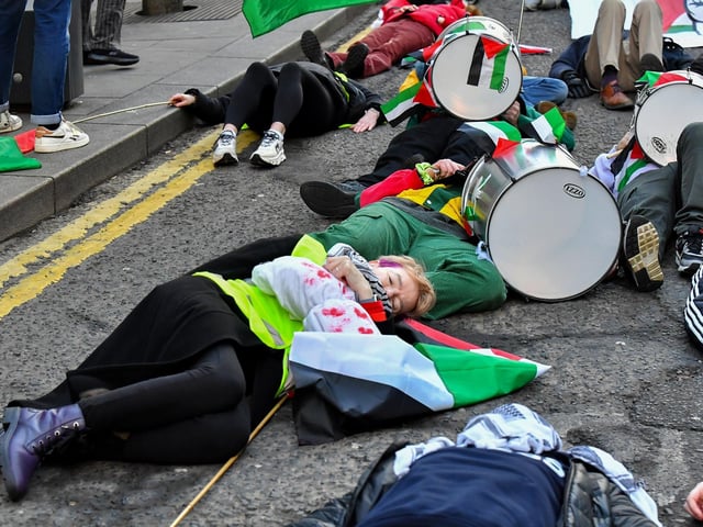 People taking part in a pro-Palestinian solidarity march “lay dead” on Shipquay Street, on Saturday afternoon to highlight the number of Palestinians who have been killed by Israel. Photo: George Sweeney