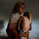 TOPSHOT - Hidaya, a 31-year-old Palestinian mother, carries her sick  18-month-old son Mohammed al-Mutawaq, who is also displaying signs of malnutrition, inside their tent at the Al-Shati refugee camp, west of Gaza City, on July 24, 2025. More than 100 aid organisations and human rights groups warned on July 23, that "mass starvation" was spreading in Gaza, as the United States said its top envoy was heading to Europe for talks on a possible ceasefire and aid corridor. (Photo by Omar AL-QATTAA / AFP) (Photo by OMAR AL-QATTAA/AFP via Getty Images)           : Hidaya, a 31-year-old Palestinian mother, carries her sick 18-month-old son Mohammed al-Mutawaq, who is also displaying signs of malnutrition, inside their tent at the Al-Shati refugee camp, west of Gaza City, on July 24, 2025. More than 100 aid organisations and human rights groups warned on July 23, that "mass starvation" was spreading in Gaza, as the United States said its top envoy was heading to Europe for talks on a possible ceasefire and aid corridor. (Photo by Omar AL-QATTAA / AFP) (Photo by OMAR AL-QATTAA/AFP via Getty Images)