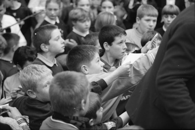 Young Manchester United fans getting autographs from Alex Ferguson.