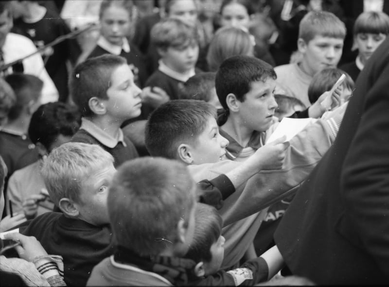 Young Manchester United fans getting autographs from Alex Ferguson.