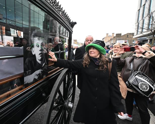 DUBLIN, IRELAND - DECEMBER 8: Members of the public touch the glass window of the carriage as the funeral procession of the late music singer Shane MacGowan takes place on December 8, 2023 in Dublin, Ireland. The public gathered on the streets of Dublin ahead of Shane MacGowan's funeral, set to take place on December 8. Born on Christmas Day in Pembury, Kent, in 1957, he's best known as the lead singer and songwriter of the Pogues. Raised in Tunbridge Wells by Irish parents, MacGowan changed up Irish folk music by infusing punk style and attitude, as showcased in the popular 1988 Christmas ballad "Fairytale of New York." He is survived by his wife, Victoria Mary Clarke, sister Siobhan, and father. (Footage by Charles McQuillan/Getty Images)