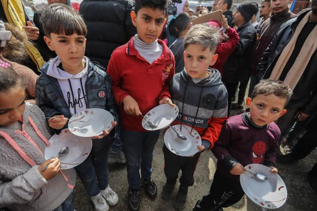 RAFAH, GAZA - MARCH 06 Palestinian children carry empty bowls during a march demanding an end to the war and an end to the famine that citizens suffer from due to the war on March 6, 2024 in Rafah, Gaza. As of Thursday February 29th, more than 30,000 people had been killed in Gaza since the start of the war on Oct. 7, according to the territory's health ministry.(Photo by Ahmad Hasaballah/Getty Images)