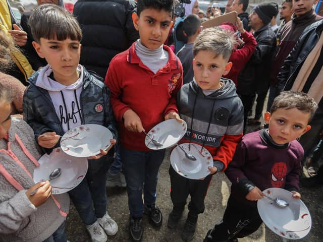 RAFAH, GAZA - MARCH 06 Palestinian children carry empty bowls during a march demanding an end to the war and an end to the famine that citizens suffer from due to the war on March 6, 2024 in Rafah, Gaza. As of Thursday February 29th, more than 30,000 people had been killed in Gaza since the start of the war on Oct. 7, according to the territory's health ministry.(Photo by Ahmad Hasaballah/Getty Images)