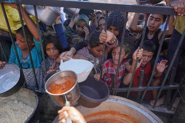 Palestinians receive cooked food rations as part of a volunteer initiative in a makeshift displacement camp in Mawasi Khan Yunis in the besieged Gaza Strip on September 3, 2024, amid the ongoing war between Israel and the Palestinian Hamas movement. (Photo by Bashar TALEB / AFP) (Photo by BASHAR TALEB/AFP via Getty Images)