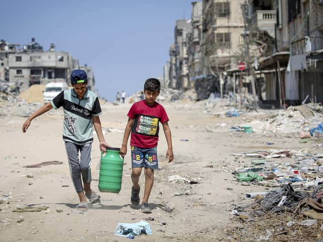 Children carry water as they walk past buildings destroyed during Israeli bombardment in Khan Yunis, on the southern Gaza Strip on April 16, 2024, as fighting continues between Israel and the Palestinian militant group Hamas. (Photo by AFP) (Photo by -/AFP via Getty Images)