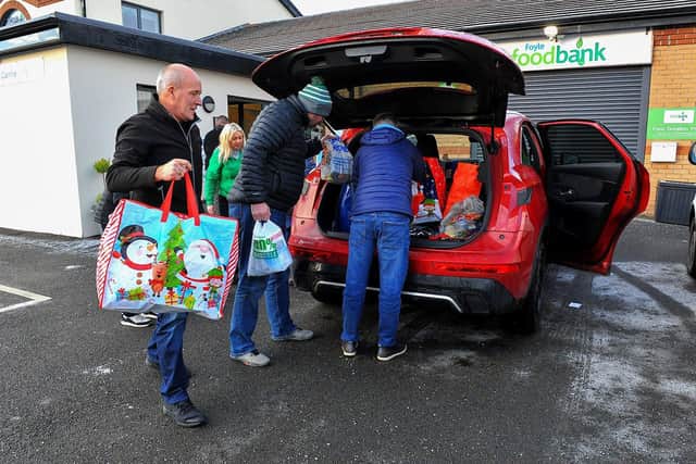 Christmas 2022: Volunteers from Invista’s Lycra plant at Maydown load a car with donations, at the Foyle Foodbank distribution Centre in Springtown Industrial Estate, for clients of Start 360 services in Castle Street. Photo: George Sweeney. DER2250GS – 28