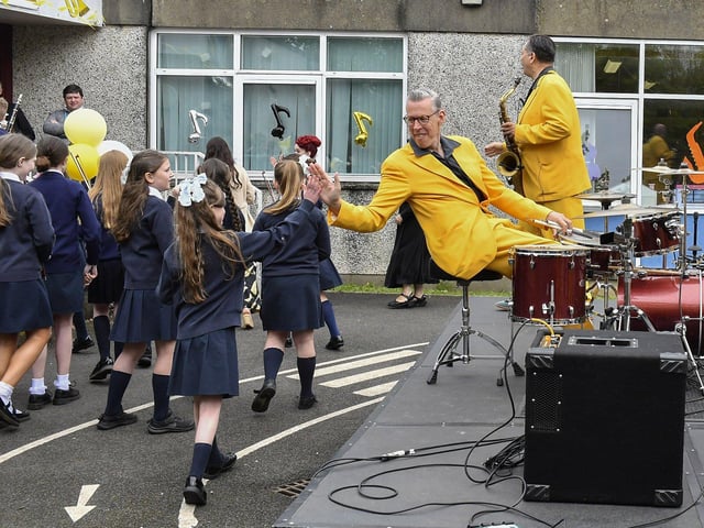 Peter Howell from the Jive Aces exchanges “high-fives” with pupils from Rosemount Primary School during the band’s visit to the school band on Thursday morning. Photo: George Sweeney