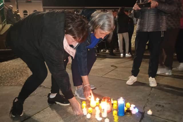 Local people place candles during a prayer vigil in Carndonagh, Donegal in solidarity with the people of Creeslough.