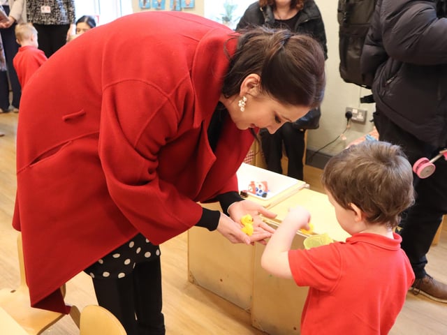 Deputy First Minister Emma Little-Pengelly smiling as a little boy hands her lots of tiny little rubber ducks at Waterside Sure Start.