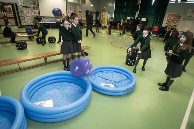 P5 pupil Olivia McLaughlin tests her dice throwing skills as fellow pupils watch on.