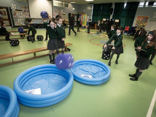 P5 pupil Olivia McLaughlin tests her dice throwing skills as fellow pupils watch on.
