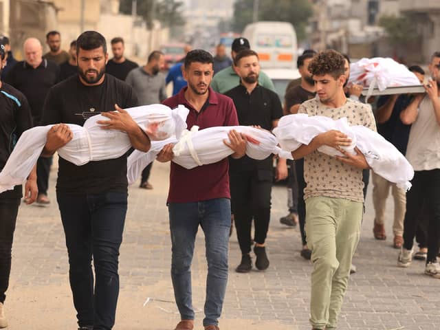 Members of the al-Zanati, family killed following an Israeli strike, are taken to a waiting vehicle to be driven to a cemetery for burial in Khan Yunis on October 23, 2023. (Photo by MAHMUD HAMS / AFP)