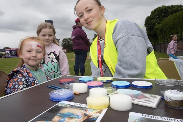 Facepainter Caitlin Barr giving young Isla Rose McDermott a makeover as Skyler Curtis looks on.