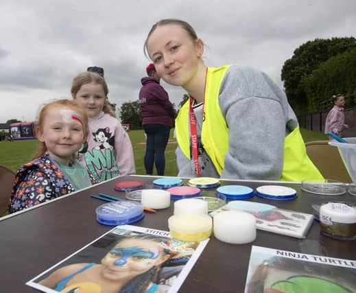 Facepainter Caitlin Barr giving young Isla Rose McDermott a makeover as Skyler Curtis looks on.