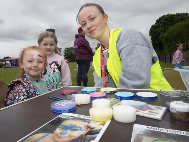 Facepainter Caitlin Barr giving young Isla Rose McDermott a makeover as Skyler Curtis looks on.