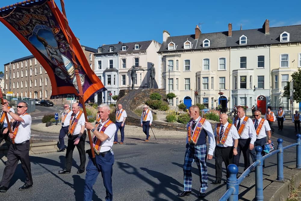 Orangemen passing Derry's Hands Across the Divide sculpture.