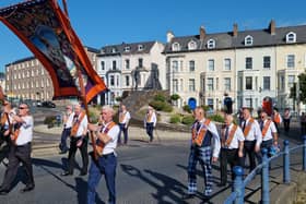 Orangemen passing Derry's Hands Across the Divide sculpture.