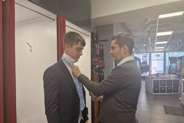 Liam McGarrigle helping a young man with his suit.