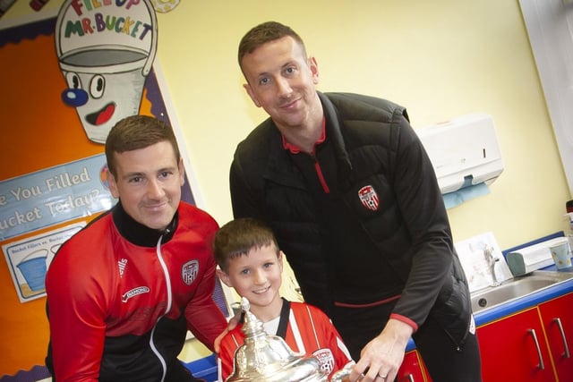Young Daniel Toland gets a picture with the FAI cup and Derry City players Patrick and Shane McEleney at Steelstown P.S. (Photo: Jim McCafferty)