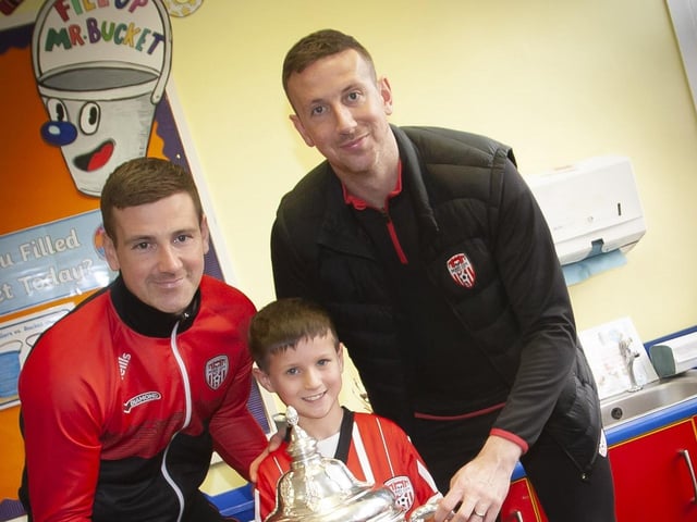 Young Daniel Toland gets a picture with the FAI cup and Derry City players Patrick and Shane McEleney at Steelstown P.S. (Photo: Jim McCafferty)