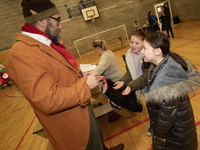 Twins Shannon and Rionagh Devlin (8) are mesmerised by the magic skills of Borris The Elf during Saturday's 'Christmas Get Together' at Long Tower Youth Club. : .