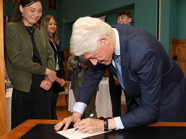 Bill Clinton signing the back of a photograph for John Hume's grandchildren