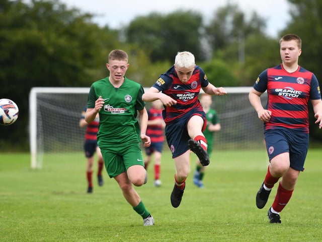 Clooney FC under-14's defender Alexander Devine volleys the ball to saferty under pressure from Cliftonville's Nathan McAteer. (Photo: Keith Moore)