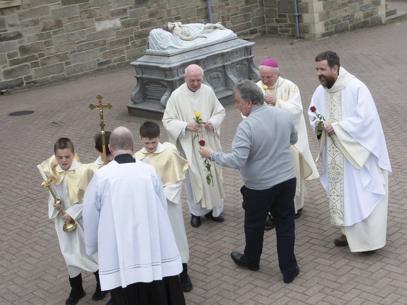 Patsy McCallion presenting roses to Bishop Donal McKeown and the clergy who officiated at Sunday’s Mass in the Long Tower Church.