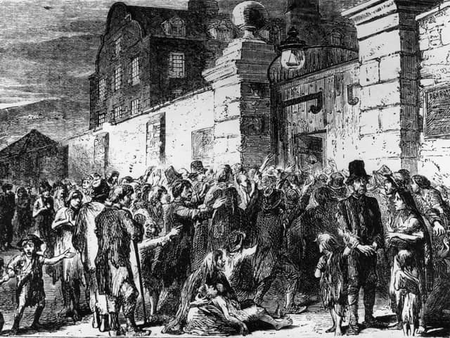 1846:  Starving peasants clamour at the gates of a workhouse during the Irish potato famine.  (Photo by Hulton Archive/Getty Images)