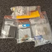 Suspected drugs and items seized along with the drug-detection kit, which is pictured in the middle of the picture, coloured blue and white.