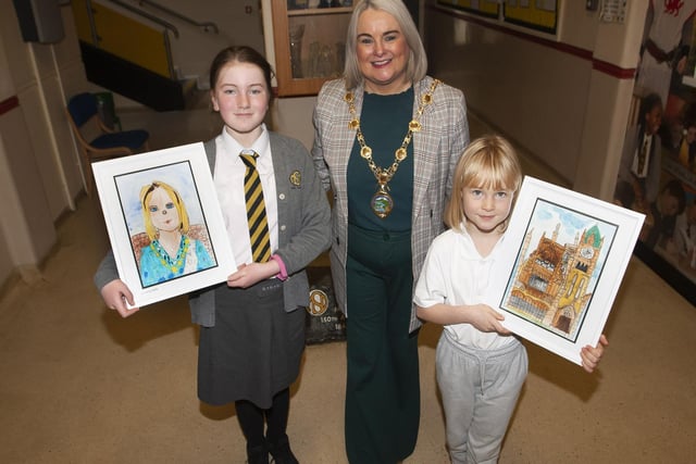 Eve and Aoife presenting the Mayor, Sandra Duffy with a portrait of herself and a portrait of the Guildhall during Monday’s visit to the Model PS.