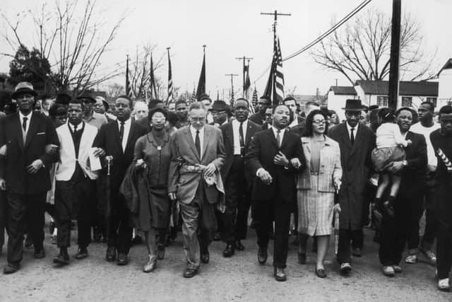 March 1965:  American civil rights campaigner Martin Luther King (1929  - 1968) and his wife Coretta Scott King lead a black voting rights march from Selma, Alabama, to the state capital in Montgomery;  among those pictured are, front row, politician and civil rights activist John Lewis (1940 – 2020), Reverend Ralph Abernathy (1926 - 1990), Ruth Harris Bunche (1906 - 1988), Nobel Prize-winning political scientist and diplomat Ralph Bunche (1904 - 1971), activist Hosea Williams (1926 – 2000 right carrying child). (Photo by William Lovelace/Daily Express/Hulton Archive/Getty Images)