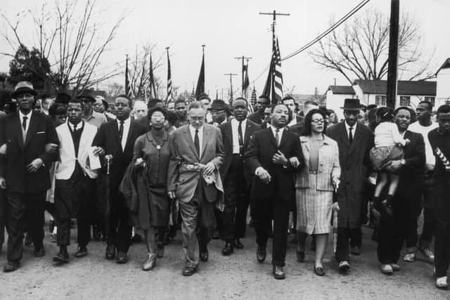 March 1965: American civil rights campaigner Martin Luther King (1929 - 1968) and his wife Coretta Scott King lead a black voting rights march from Selma, Alabama, to the state capital in Montgomery; among those pictured are, front row, politician and civil rights activist John Lewis (1940 – 2020), Reverend Ralph Abernathy (1926 - 1990), Ruth Harris Bunche (1906 - 1988), Nobel Prize-winning political scientist and diplomat Ralph Bunche (1904 - 1971), activist Hosea Williams (1926 – 2000 right carrying child). (Photo by William Lovelace/Daily Express/Hulton Archive/Getty Images)