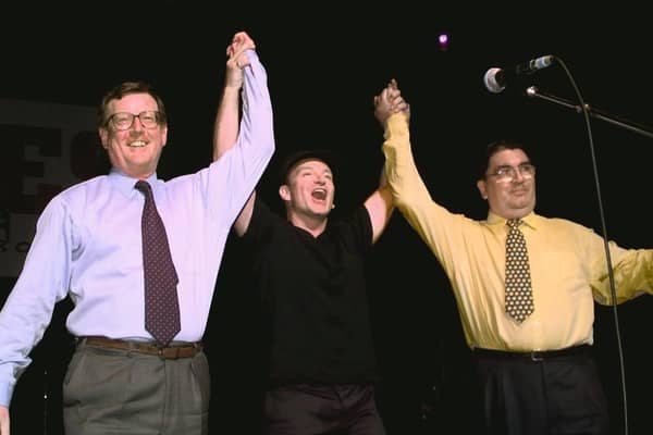 Irish rock band U2's lead singer Bono (C) holds up the arms of Ulster Unionist leader David Trimble (L) and SDLP leader John Hume on stage during a concert given by U2 and Ash at the Waterfront concert hall to promote the yes vote for Friday's peace referendum. Photo credit: GERRY PENNY/AFP via Getty Images