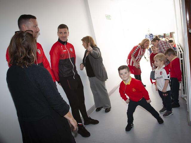 One young Steelstown pupil shows some nifty footwork of his own to Derry City players Shane and Patrick McEleney and Michael Duffy on Tuesday. (Photo: Jim McCafferty)