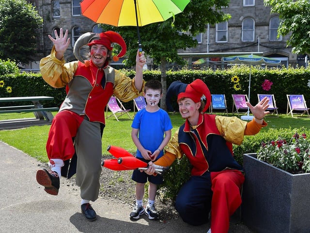 Four year old Eissa Coyle poses with clowns, in the Peace Garden, during the Carnival of Colours Festival. Photo: George Sweeney