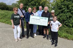 Henry McLaughlin displaying a cheque of money raised from the 2025 Scalp Walk with members of the Derry Concern Group