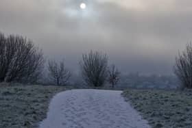 The hazy low winter sun hovers over the snow covered roofs of homes in the Waterside area of Derry.