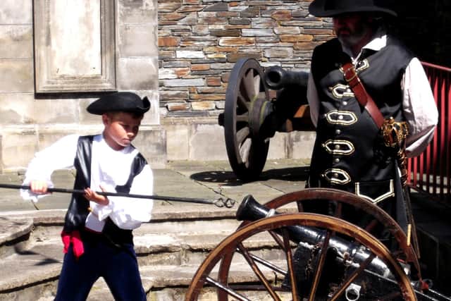 A boy loads the canon under instruction at The Guns Of The Siege display.