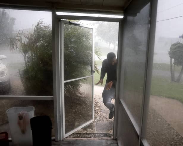 FORT MYERS, FLORIDA - OCTOBER 09: Chris Williams runs through a rain storm as he packs his car to evacuate his apartment before Hurricane Milton's arrival on October 09, 2024, in Fort Myers, Florida. People are preparing for the storm, which could be a Cat 3 when it makes landfall on Wednesday evening. (Photo by Joe Raedle/Getty Images)