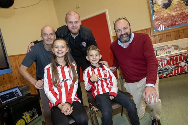 Derry manager Mark Connolly pictured with his children - Ora and Rohan, Mr Andy McDermott, school caretaker and principal Mr. Feargal Friel on Friday. (Photos: Jim McCafferty Photography)