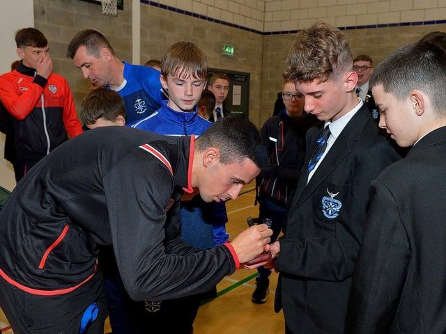Derry Citys Jordon McEneff signs autographs for pupils during a visit to the school, with the FAI Cup, on Monday . Photo: George Sweeney. DER2247GS 26
