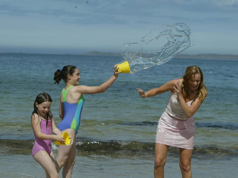 Laura Henry and Shannon Walsh from Ballymena give Shannon's mum Siobhan a little help cooling down at Ballyliffin yesterday. (0508JB71):Derry youngsters enjoying summer in August 2003