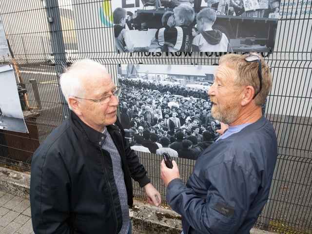 Sean Collins and exhibition curator Jim Collins discuss one of the photos during Friday evening's exhibition launch outside Pilot's Row Centre.