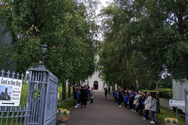 Schoolchildren and others forming a guard of honour ahead of the funeral procession arriving yesterday.