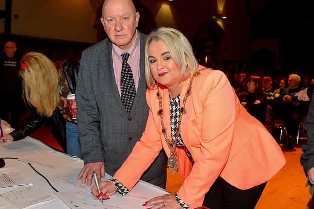 National Union of Journalists assistant general secretary Séamus Dooley loos on as Mayor Sandra Duffy signs a petition to save Radio Foyle at the public meeting, held in the Guildhall, opposing planned cuts to jobs and services at the local radio station. George Sweeney. DER2301GS – 13