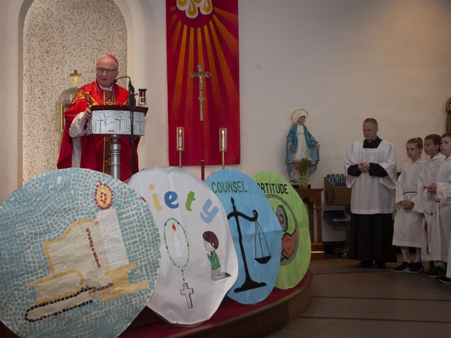 Some of the artwork on display from the various schools is displayed at the front of the altar as Bishop Donal McKeown addresses the schoolchildren.